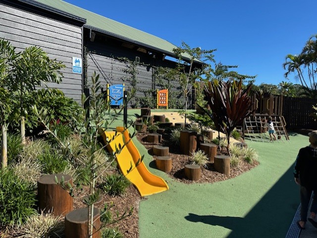 Completed nature playground with slide, balance logs and planting.